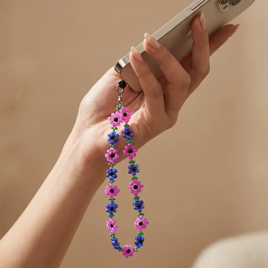 Bunte Handykette mit Blumen aus Perlen in Blau und Rosa, befestigt an einem Smartphone, modisches Accessoire.