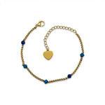 Goldenes Edelstahl Armband mit Herz-Anhänger und blauen Perlen auf weißem Hintergrund