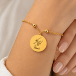 Goldenes personalisiertes Edelstahl Armband mit rundem Anhänger, Hände-Motiv mit Herz und Gravur „Noah“, am Handgelenk getragen