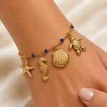 Goldenes Sommer Armband mit Meeres Charms getragen am Handgelenk