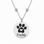 Silbernes personalisiertes Edelstahl Armband mit rundem Anhänger, Pfotenmotiv mit Herz und Name Freddy auf weißem Hintergrund