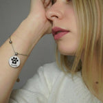 Frau trägt ein silberfarbenes Edelstahlarmband mit rundem Anhänger, graviert mit einer Pfote und dem Namen „Freddy“, personalisiertes Tierarmband für Hund oder Katze.