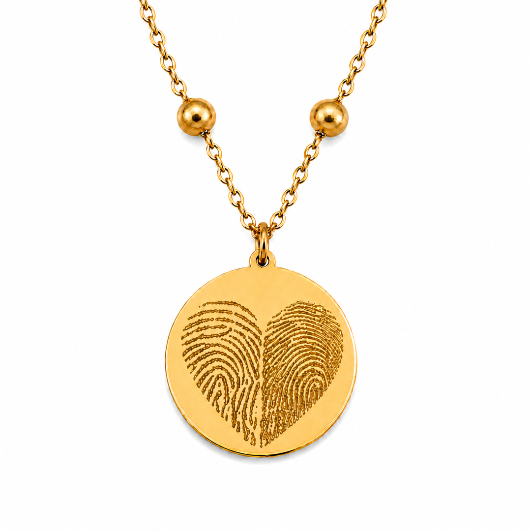 Goldene personalisierte Edelstahl Halskette mit rundem Anhänger und Fingerabdruck Herz Gravur auf weißem Hintergrund