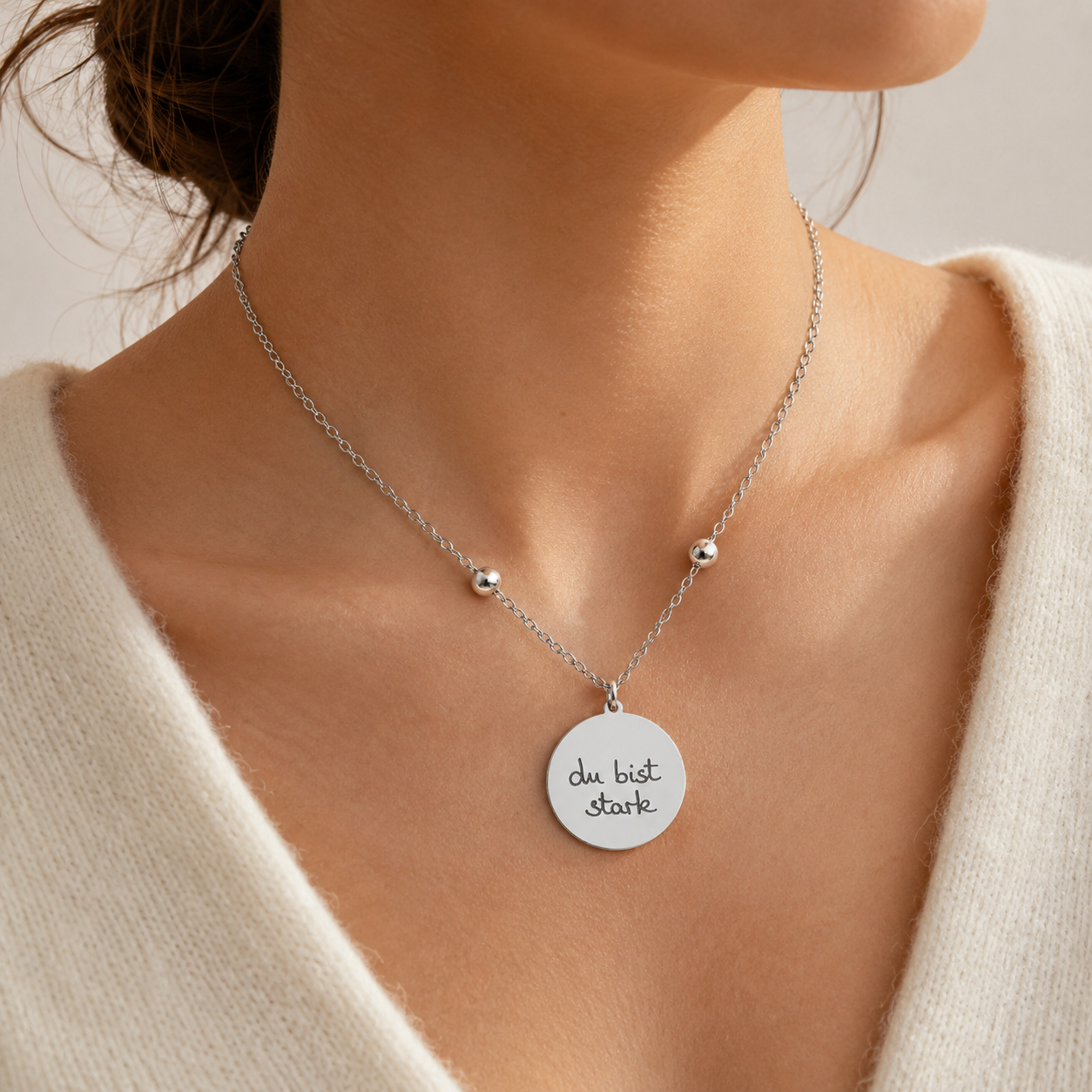 Silberne personalisierte Edelstahl Halskette mit rundem Anhänger und Gravur „du bist stark“, am Hals getragen