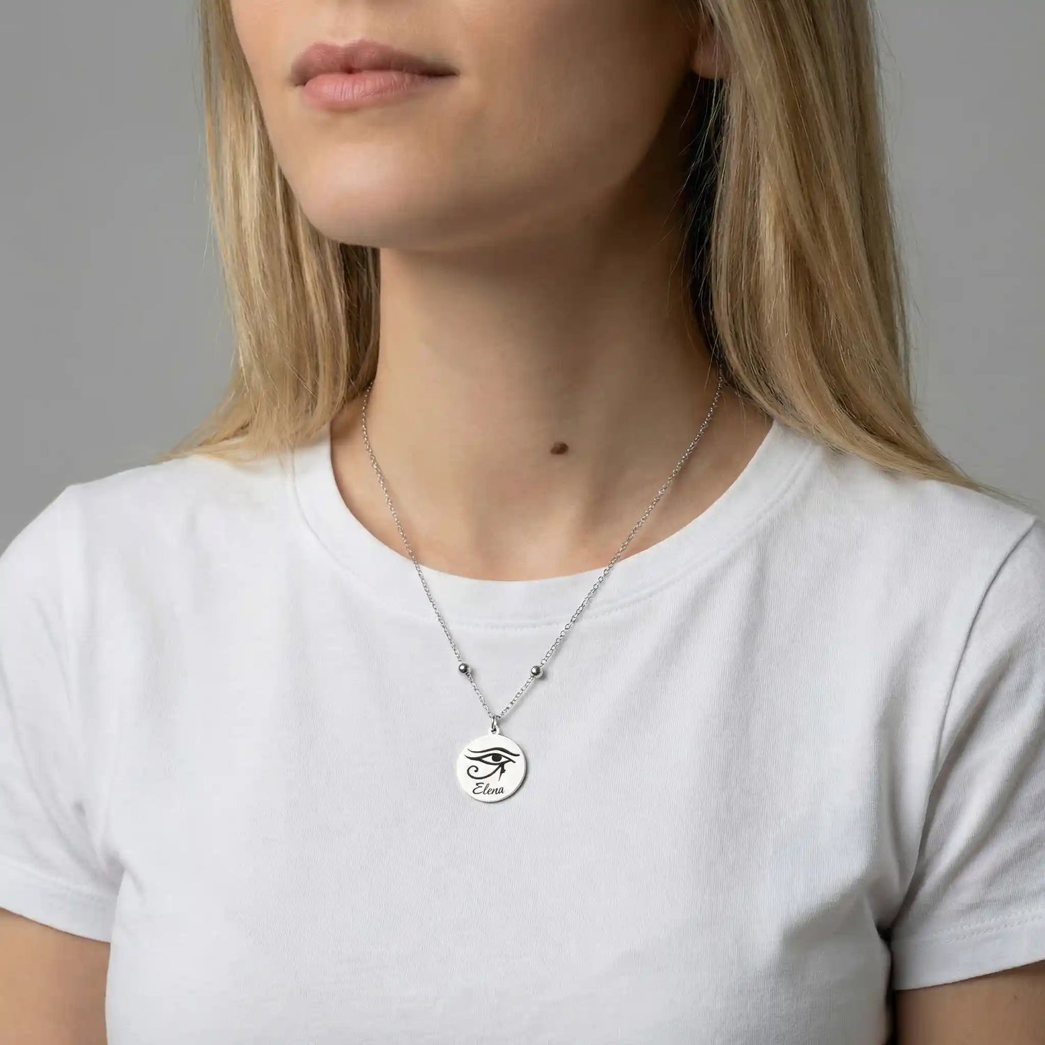 Frau trägt eine silberfarbene Edelstahlkette mit rundem Anhänger, graviert mit einem astrologischen Symbol und Namen, minimalistisches und elegantes Design.
