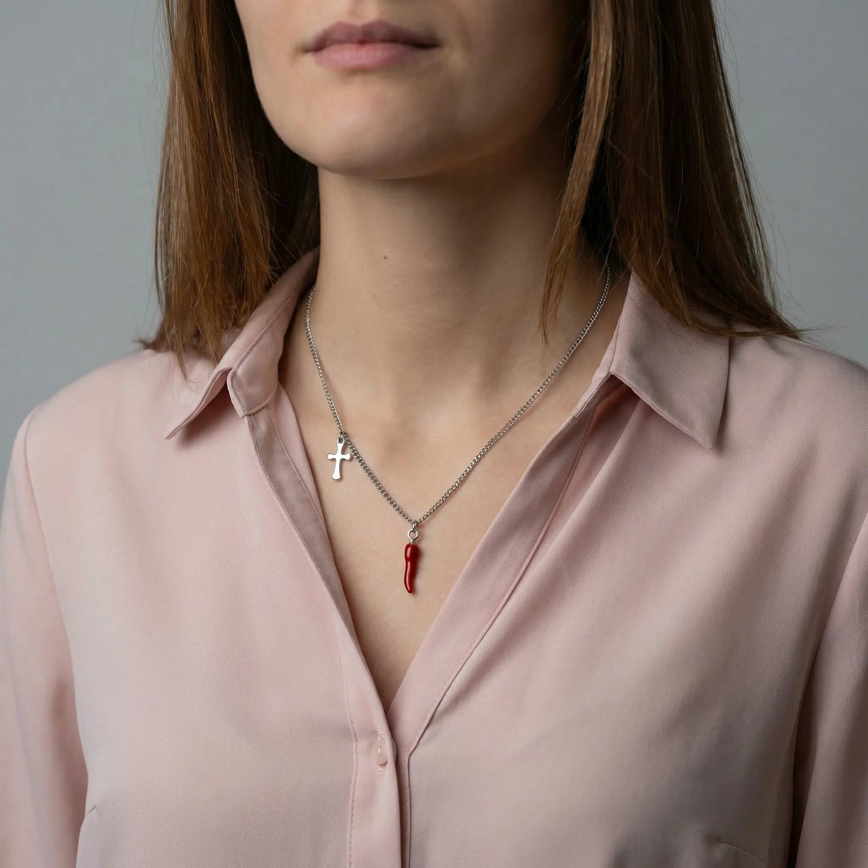 Frau trägt eine silberfarbene Edelstahlkette mit rotem Chili-Anhänger und Kreuz-Detail am Hals.