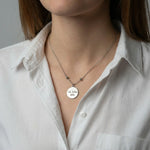 Frau trägt eine silberfarbene Edelstahlkette mit rundem Anhänger und gravierter Botschaft am Hals.