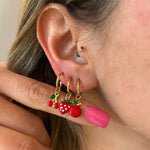 Frau trägt goldene Creolen mit Kirschen-, Erdbeer- und Apfel-Anhängern am Ohr als sommerlichen Schmucklook