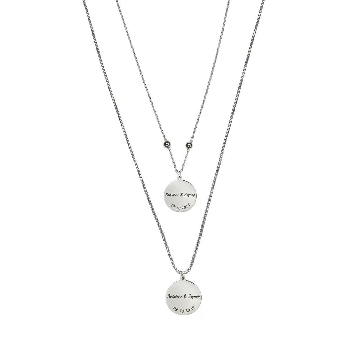 Zwei silberfarbene Edelstahl-Partnerhalsketten mit runden Anhängern, personalisiert mit Namen und Datum, minimalistisches Schmuckdesign.