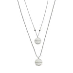 Zwei silberfarbene Edelstahl-Partnerhalsketten mit runden Anhängern, personalisiert mit Namen und Datum, minimalistisches Schmuckdesign.