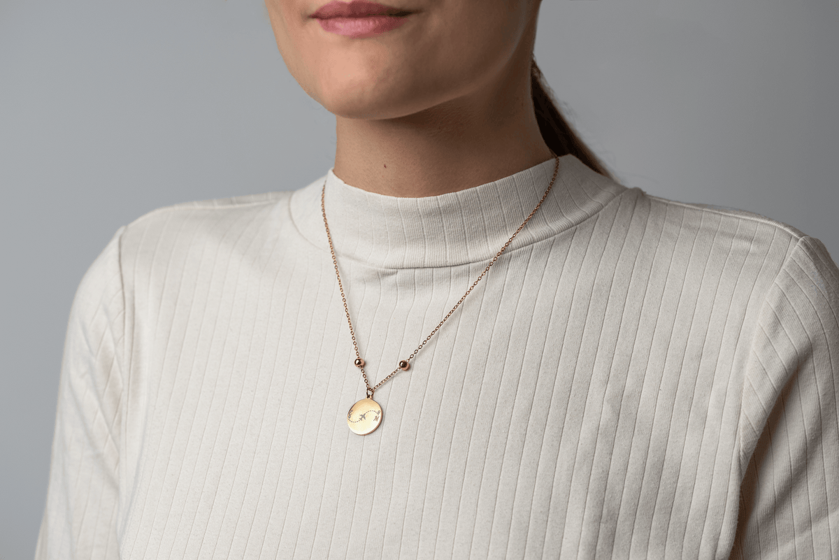 Nahaufnahme der goldenen Travel Connection Halskette mit Weltkarte an einem Modell